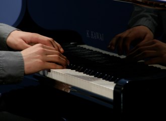 grand piano reflecting hands on keys